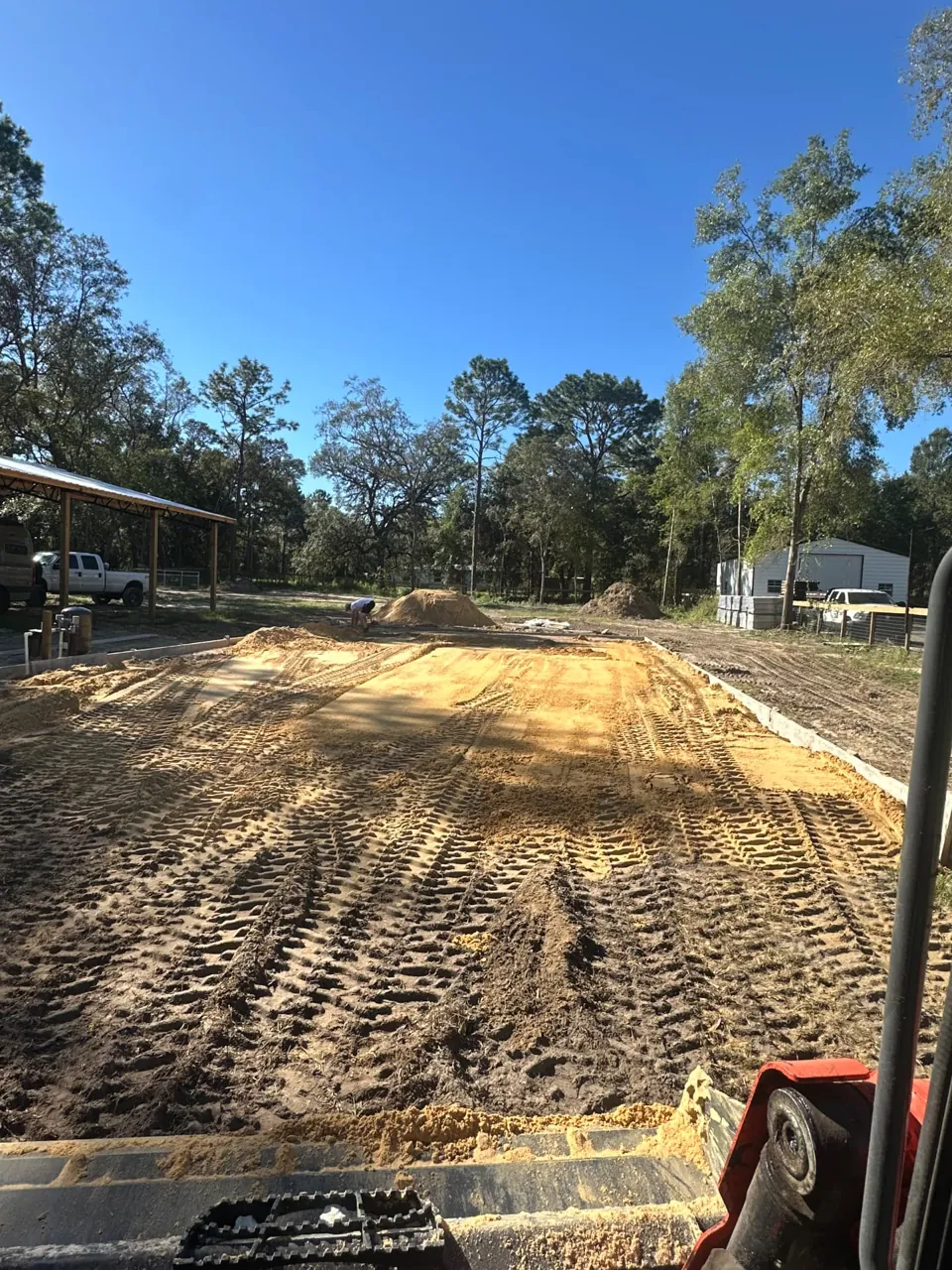 View from a skid steer bucket across a sand pad during site grading