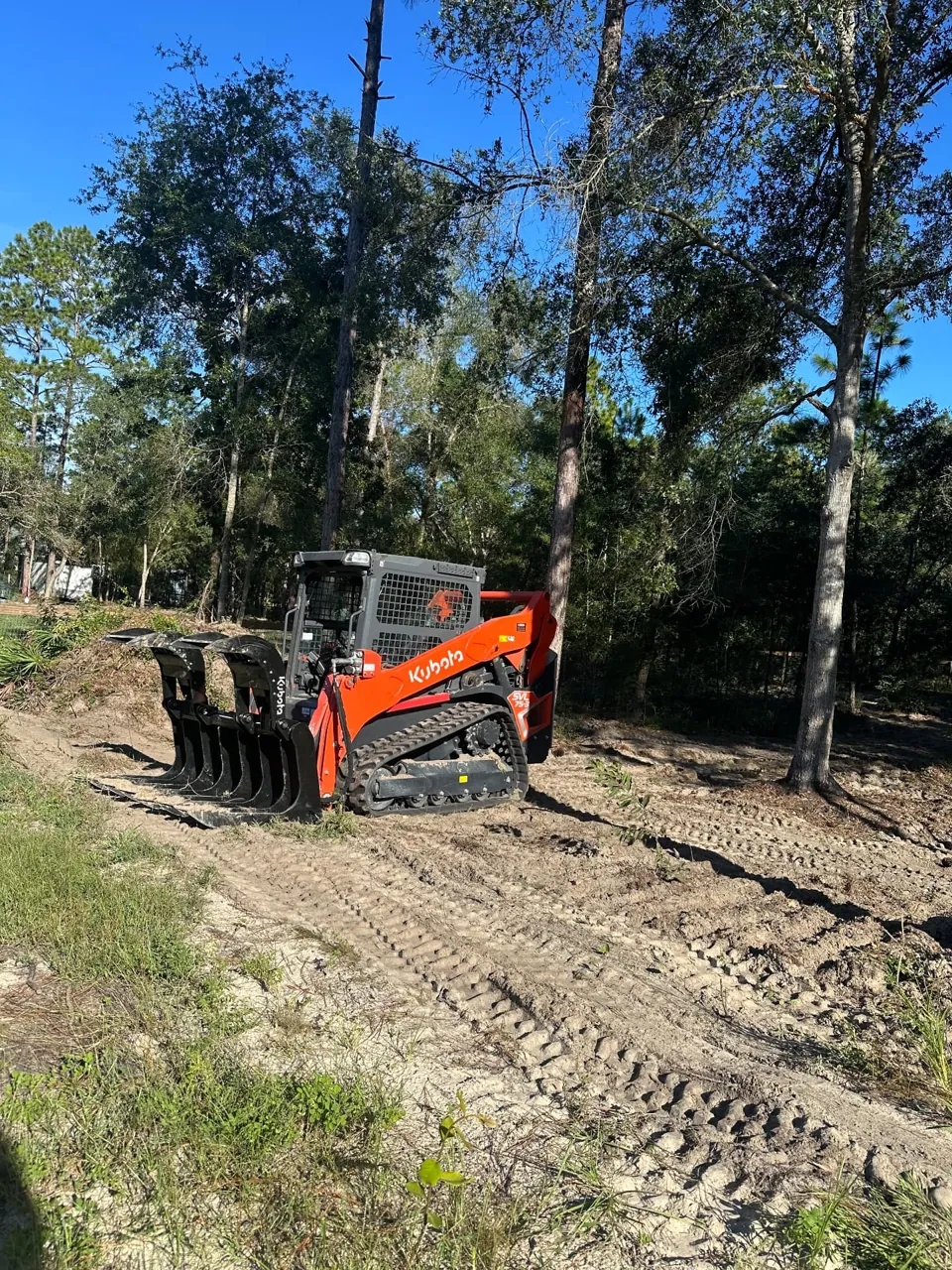 Gibson Development Group Kubota SVL75-3 with grapple on cleared ground among existing trees
