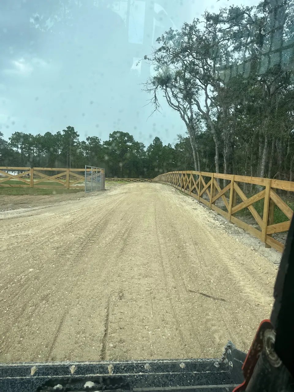 Road base driveway surface being graded along a wooden fence